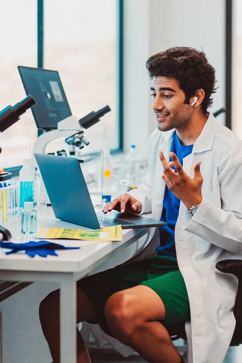 Scientist in a lab coat working beside a microscope