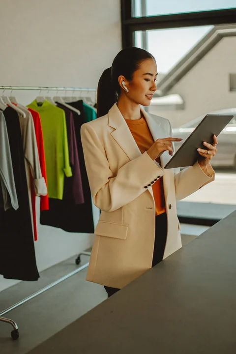 Store manager checking stock on a tablet beside clothing rails